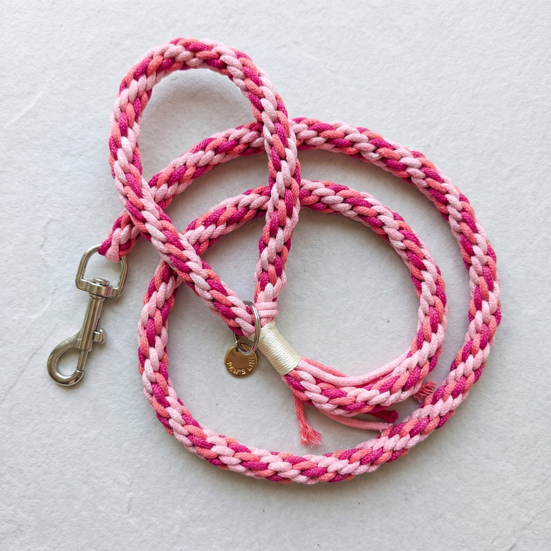 The hand-woven braided cotton rope dog leash in Berry Sorbet loosely looped on a grey textured background surface. color:Berry Sorbet