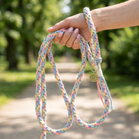 A close-up of a person holding the Cotton Candy Swirl rope leash by its loop, displaying its full length during an outdoor walk.
