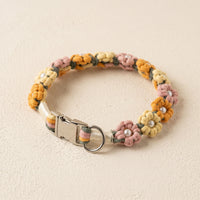 Paw's Line macrame flower dog collar. color:Autumn Blossom. Displayed as a standalone loop on a warm cream backdrop with a metal buckle.