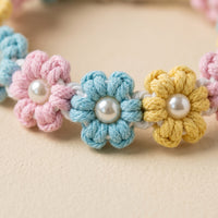 Close-up macro view highlighting the repeating handmade blue, pink, and yellow woven macrame flowers with central pearl beads.