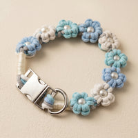 Paw's Line macrame flower dog collar. Displayed as a standalone loop on a warm cream backdrop with a metal buckle. color:Glacier Mist