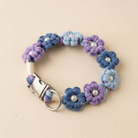 Paw's Line macrame flower dog collar. color:Lavender Twilight. Displayed as a standalone loop on a warm cream backdrop with a metal buckle.