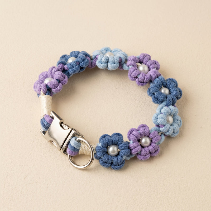 Paw's Line macrame flower dog collar. color:Lavender Twilight. Displayed as a standalone loop on a warm cream backdrop with a metal buckle.