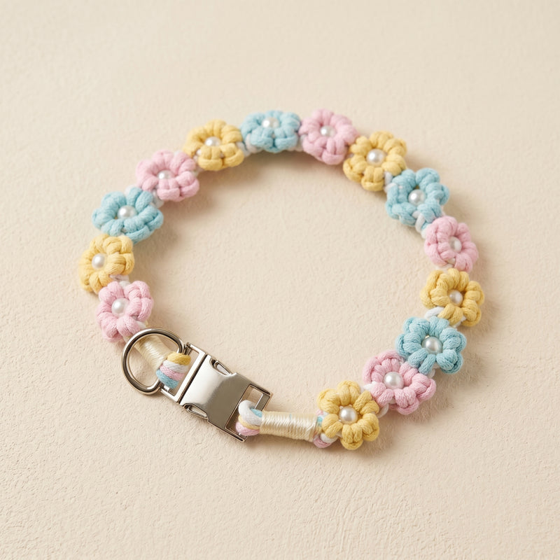 Paw's Line macrame flower dog collar. color:Pastel Candy. Displayed as a standalone loop on a warm cream backdrop with a metal buckle.