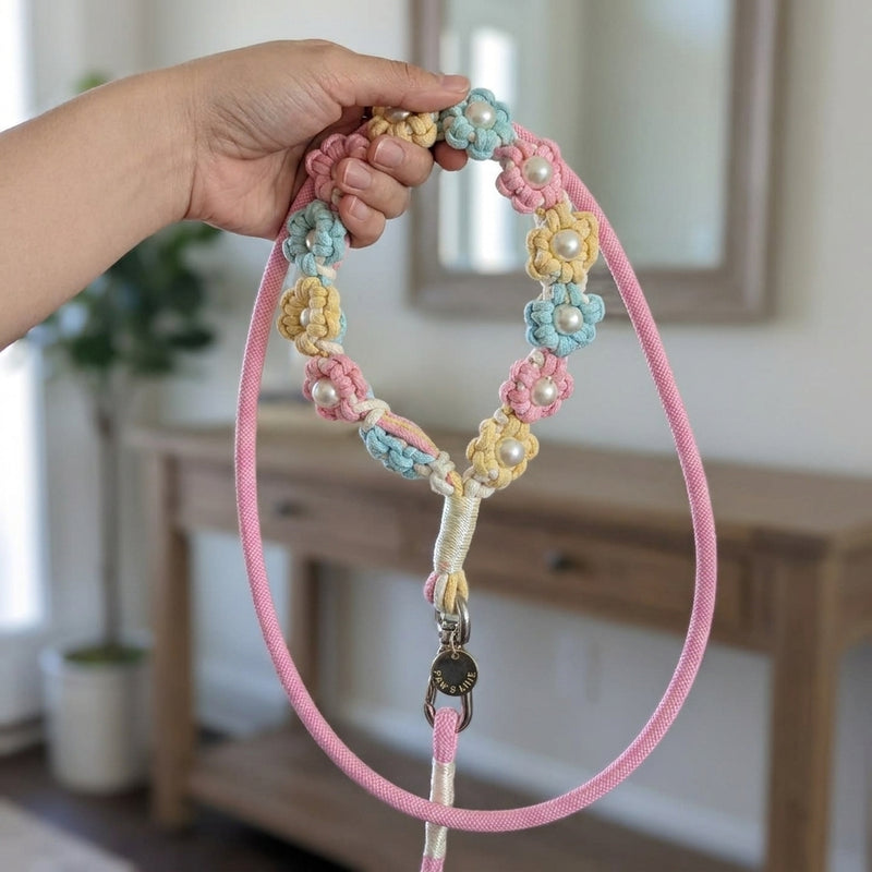 A woman holding The Pearl & Blossom Dog Leash - Pastel Candy by its floral macrame handle loop in a bright, elegant home entryway.