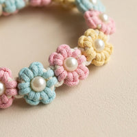 Macro shot of the repeating blue, pink, and yellow woven flowers with central pearls on the Paw's Line Pastel Candy macrame collar.