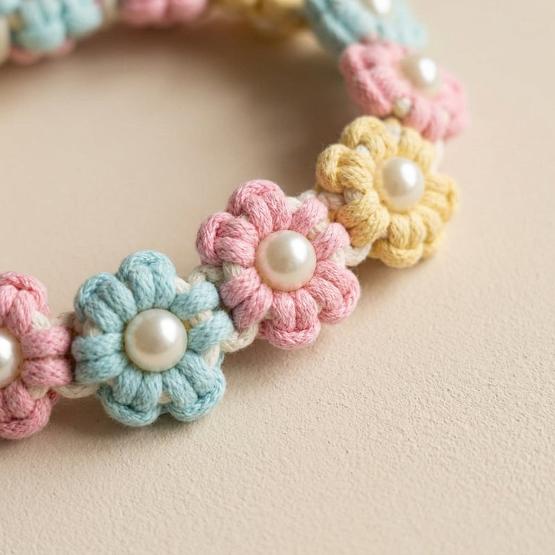 Macro shot of the repeating blue, pink, and yellow woven flowers with central pearls on the Paw's Line Pastel Candy macrame collar.