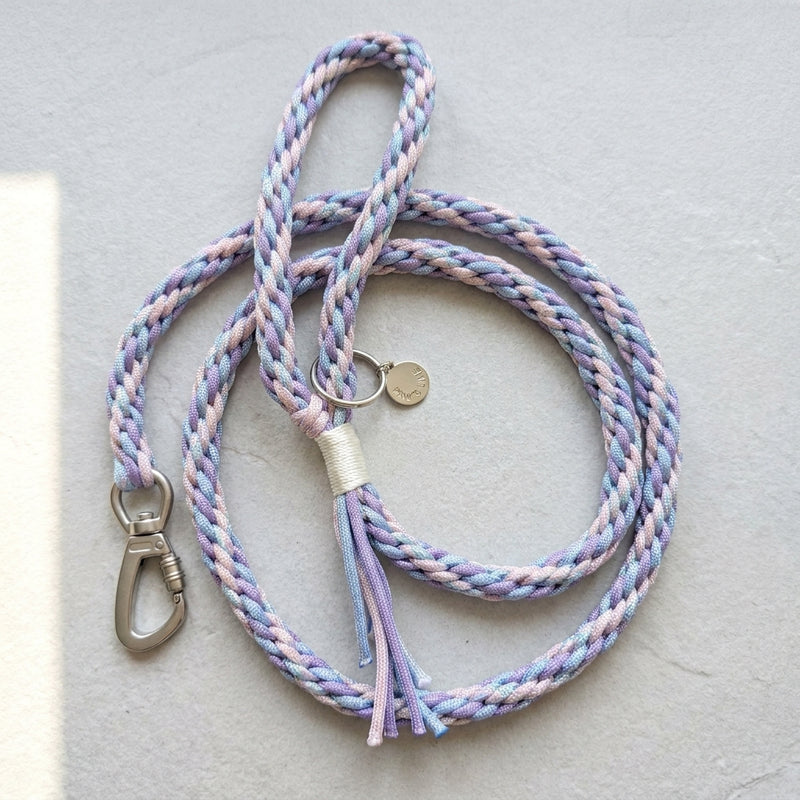 The Traverse Braided Paracord Leash in Lavender Frost by Paw's Line, loosely looped on a grey textured studio surface. color:Lavendar Frost