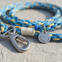 Close-up detail of the Ocean Breeze variant of The Traverse Braided Paracord Leash showing the rugged weave and silver tag. color:all